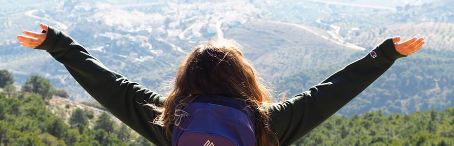 Student with arms outstretched overlooking a valley in Europe